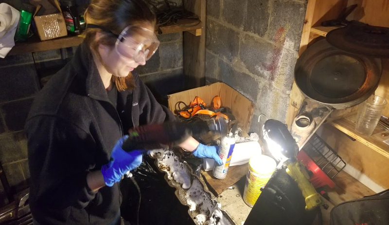 Rochelle hitting my sludgy-encrusted valve cover with some foaming cleaner and a wire brush on a drill.